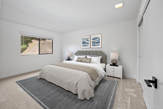 bedroom with light colored carpet, baseboards, and a closet