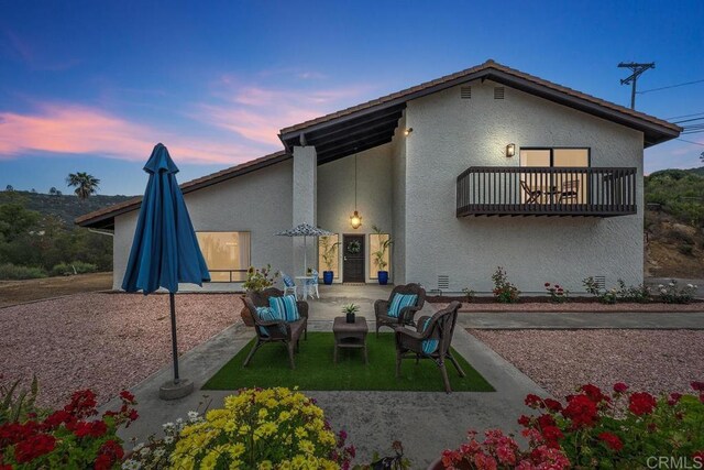 rear view of property with stucco siding, a patio area, and an outdoor living space