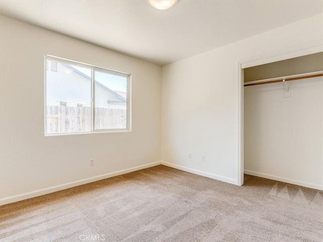 unfurnished bedroom with baseboards, carpet flooring, and a closet