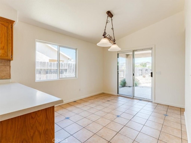 unfurnished dining area with a wealth of natural light, vaulted ceiling, baseboards, and light tile patterned flooring