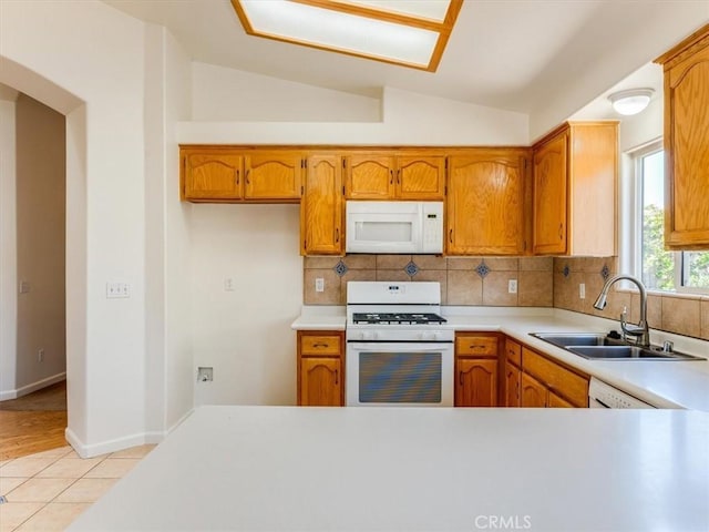 kitchen featuring a sink, lofted ceiling, white appliances, and light countertops
