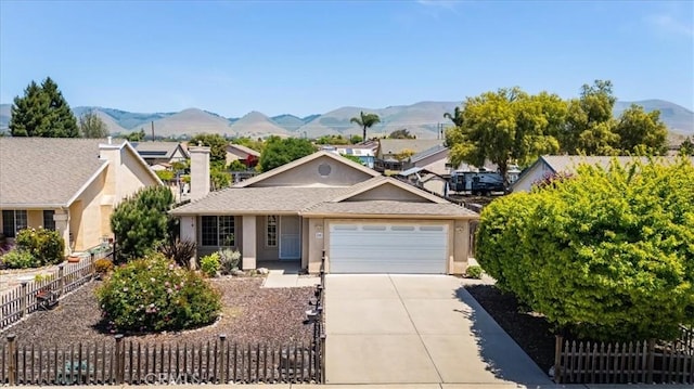 ranch-style house featuring a mountain view, a garage, stucco siding, driveway, and fence private yard