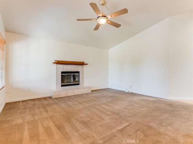 unfurnished living room featuring lofted ceiling, a ceiling fan, carpet, baseboards, and a tiled fireplace