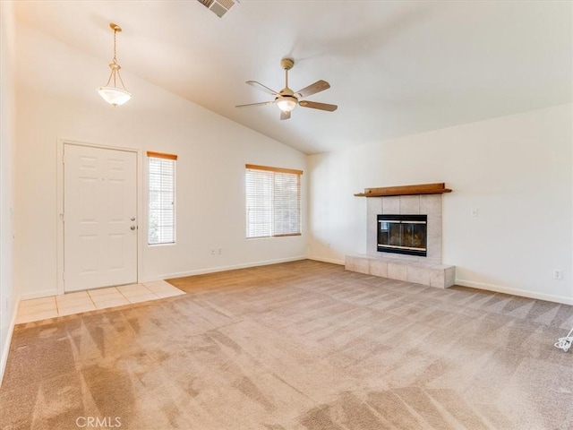 unfurnished living room featuring vaulted ceiling, ceiling fan, carpet flooring, baseboards, and a tile fireplace