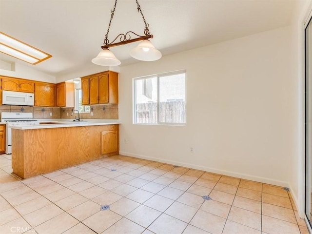 kitchen with a peninsula, brown cabinets, white appliances, light countertops, and tasteful backsplash