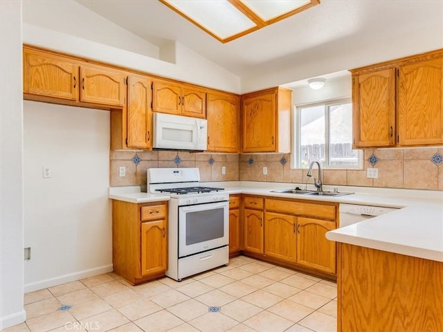 kitchen featuring brown cabinetry, a sink, and white appliances