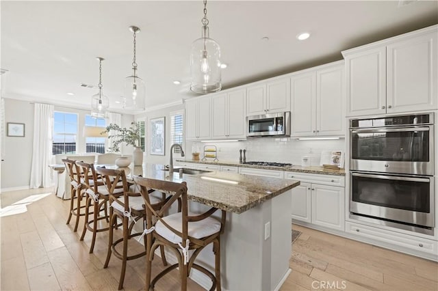 29034 Via Patina, Valencia, CA 91354 - kitchen with stainless steel appliances, recessed lighting, light wood-type flooring, an island with sink, and backsplash