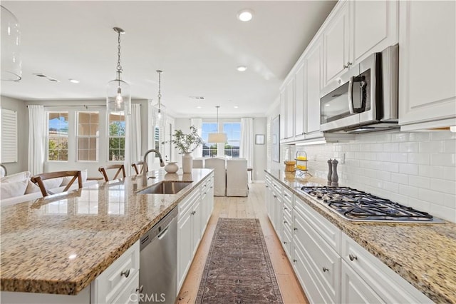 29034 Via Patina, Valencia, CA 91354 - kitchen with appliances with stainless steel finishes, light wood-style floors, white cabinetry, decorative backsplash, and a spacious island