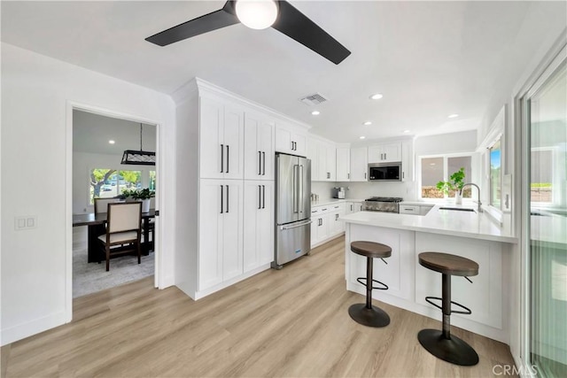 1760 N Yurok St, Orange, CA 92867 - kitchen featuring stainless steel appliances, a kitchen breakfast bar, light wood-type flooring, white cabinetry, and light countertops
