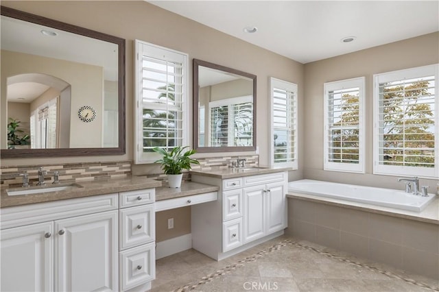 full bathroom with a garden tub, vanity, backsplash, and tile patterned floors