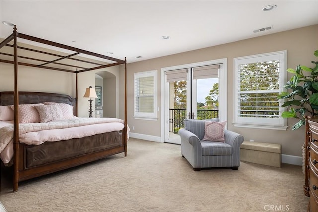 bedroom with access to outside, baseboards, light colored carpet, and arched walkways