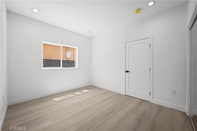 spare room with baseboards, recessed lighting, and wood finished floors