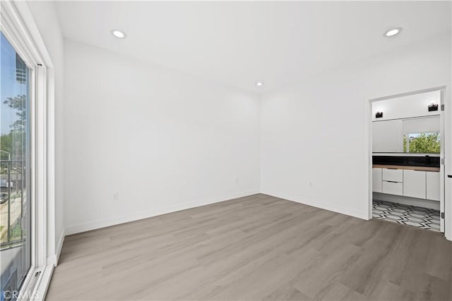 unfurnished living room with light wood-style flooring, baseboards, and recessed lighting