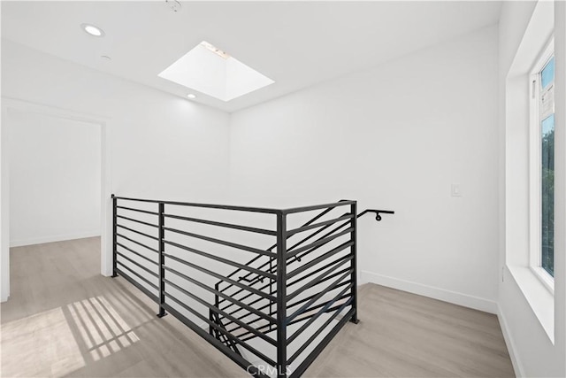 stairs featuring baseboards, a healthy amount of sunlight, a skylight, and wood finished floors