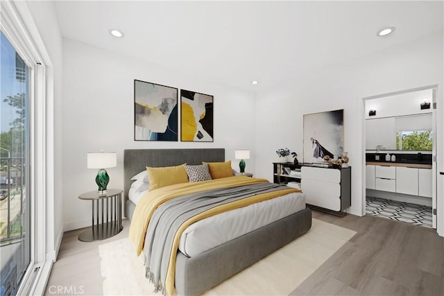 bedroom featuring light wood finished floors, ensuite bathroom, and recessed lighting