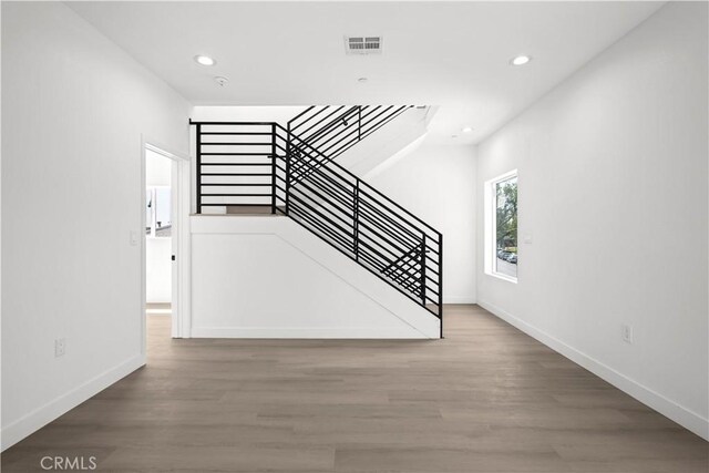 unfurnished living room with stairs, wood finished floors, visible vents, and recessed lighting