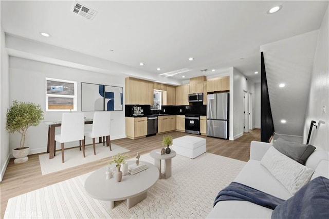 living room with baseboards, recessed lighting, light wood-style floors, and visible vents