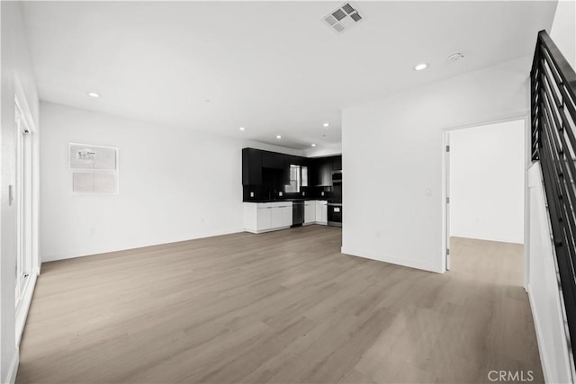 unfurnished living room with light wood-style floors, visible vents, and recessed lighting