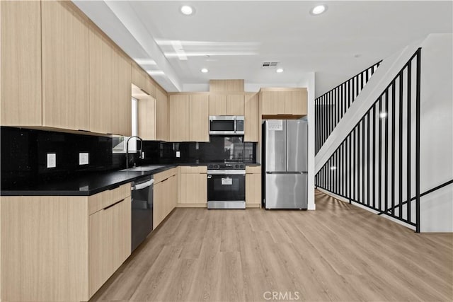 kitchen featuring a sink, stainless steel appliances, light brown cabinetry, and modern cabinets