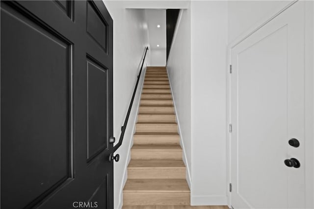 staircase featuring baseboards and wood finished floors