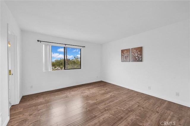 empty room featuring wood finished floors and baseboards