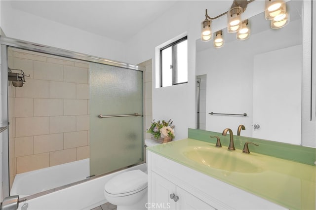 full bathroom featuring toilet, combined bath / shower with glass door, and vanity