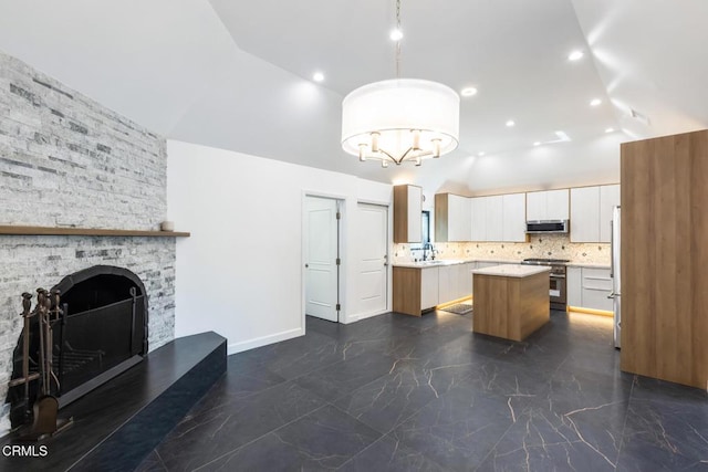kitchen with appliances with stainless steel finishes, dark marble finish floors, a center island, range hood, and high vaulted ceiling