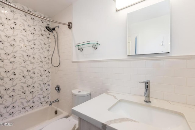 bathroom with tile walls, shower / washtub combination, toilet, and vanity