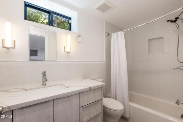 full bathroom featuring toilet, vanity, shower / bathtub combination with curtain, and tile walls