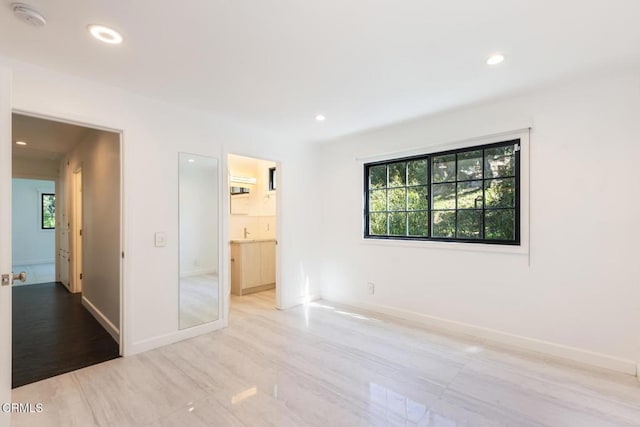 unfurnished bedroom featuring multiple windows, recessed lighting, baseboards, and ensuite bathroom