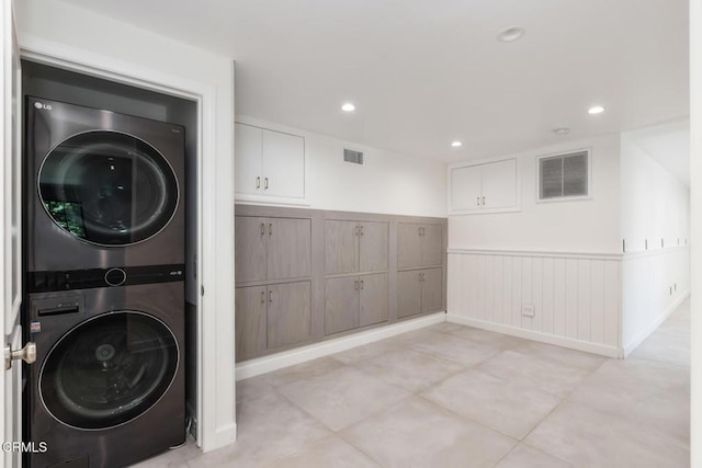 laundry area with stacked washer / dryer, wainscoting, recessed lighting, and light tile patterned floors