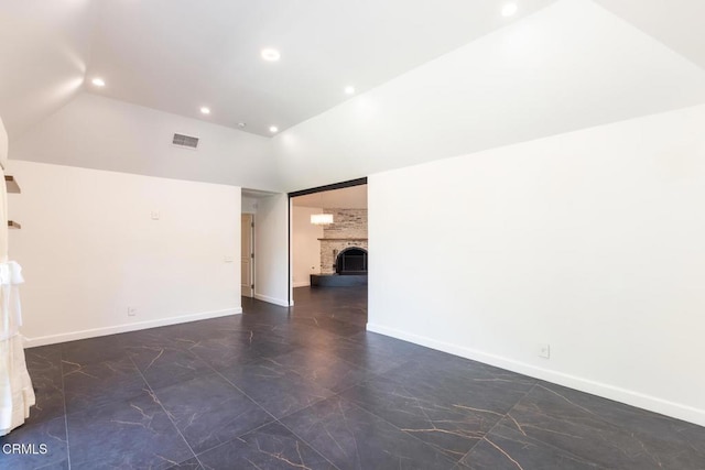 spare room with dark marble finish floors, recessed lighting, vaulted ceiling, a fireplace, and baseboards