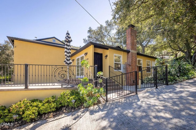 7580 Mcgroarty Ter, Tujunga, CA 91042 - view of front of home featuring stucco siding, a fenced front yard, a chimney, and a gate