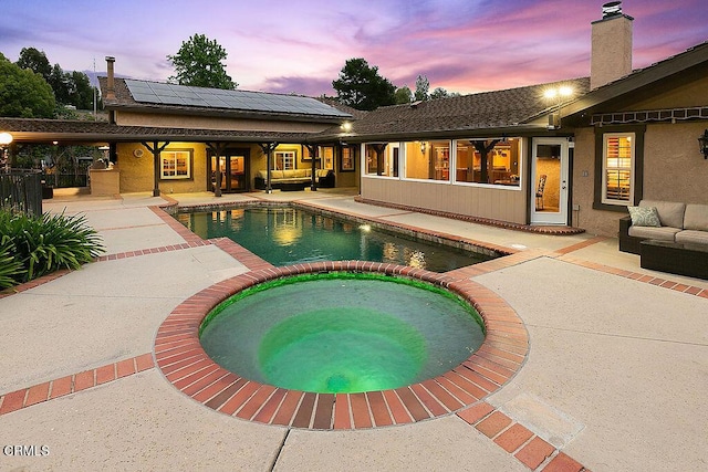 pool at dusk with a patio, an outdoor living space, and a pool with connected hot tub