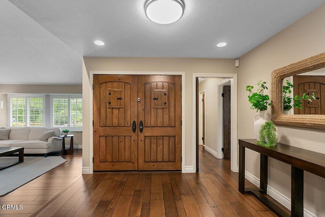 foyer entrance featuring a textured ceiling, baseboards, dark wood-style flooring, and recessed lighting