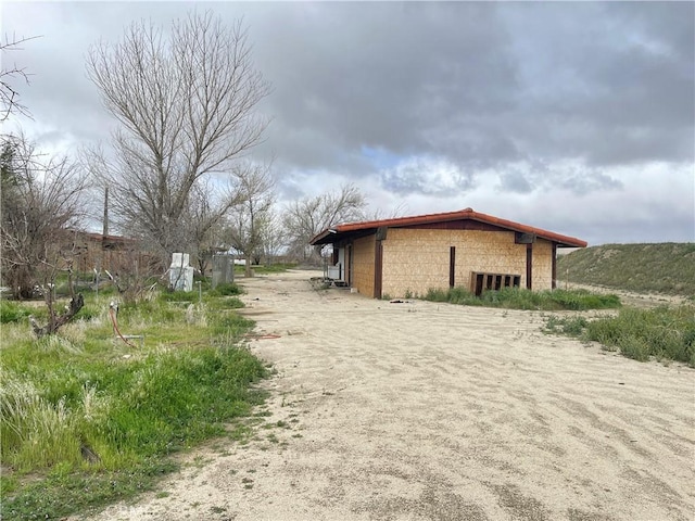 view of side of home with concrete block siding and an outdoor structure