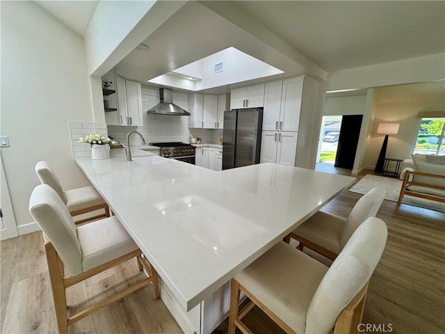 29521 Via, San Sebastian, Laguna Niguel, CA 92677 - kitchen featuring wall chimney exhaust hood, appliances with stainless steel finishes, a sink, a peninsula, and light countertops