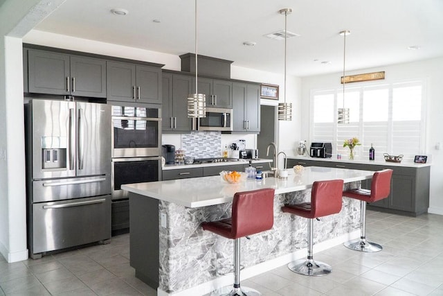 2373 Crater Ave, Rialto, CA 92377 - kitchen featuring stainless steel appliances, light countertops, a sink, a breakfast bar area, and an island with sink