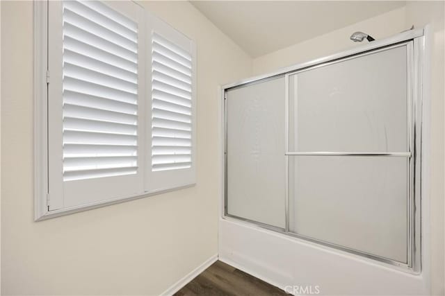 bathroom featuring wood finished floors, shower / bath combination with glass door, and baseboards