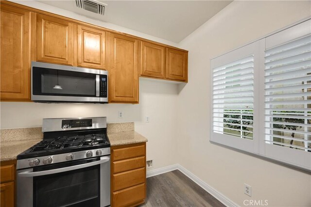 kitchen featuring stainless steel appliances, dark wood-style floors, brown cabinets, and baseboards