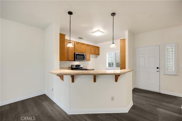 kitchen featuring stainless steel appliances, dark wood finished floors, brown cabinetry, and baseboards