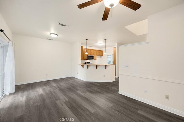 unfurnished living room featuring dark wood-style flooring, a ceiling fan, and baseboards
