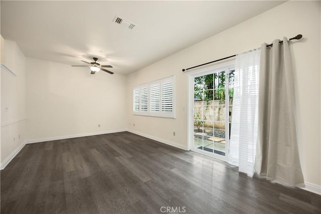 unfurnished room featuring dark wood-style flooring, a ceiling fan, and baseboards