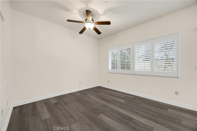 unfurnished room with dark wood-type flooring, a ceiling fan, and baseboards