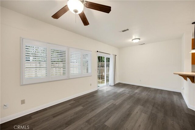 unfurnished living room featuring dark wood-style flooring, baseboards, and a ceiling fan