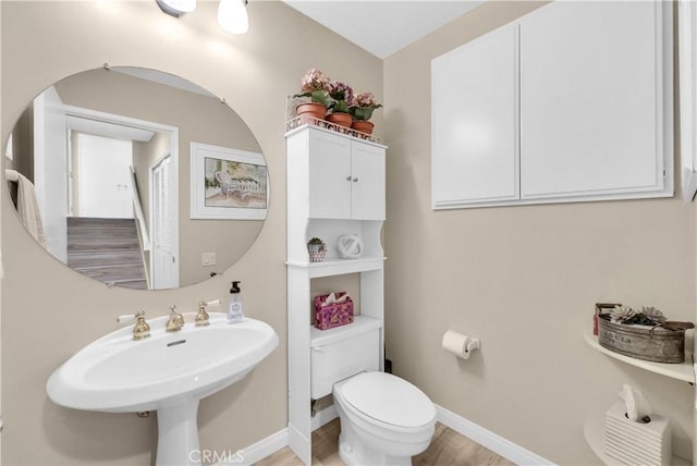 bathroom with toilet, baseboards, a sink, and wood finished floors