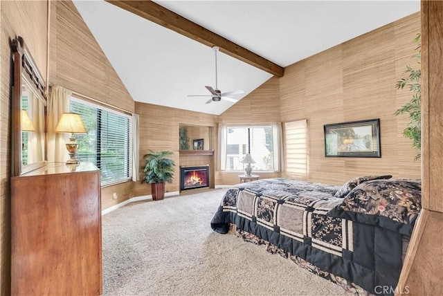bedroom with carpet, beam ceiling, a glass covered fireplace, baseboards, and high vaulted ceiling