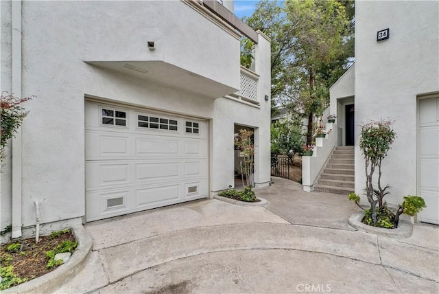 view of property exterior with stucco siding, an attached garage, driveway, and stairway