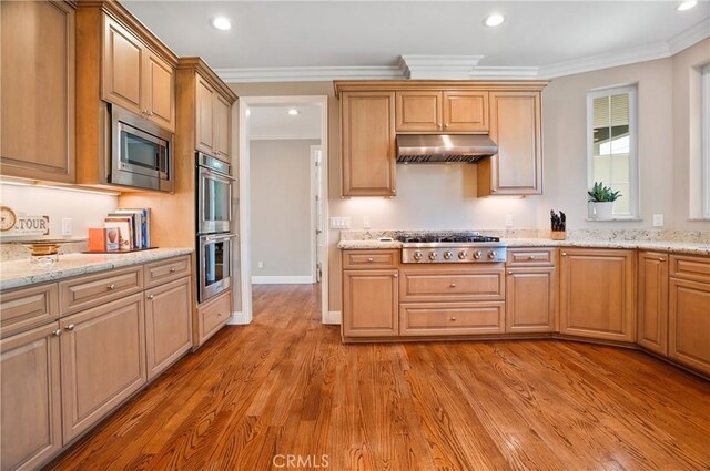 kitchen featuring appliances with stainless steel finishes, under cabinet range hood, ornamental molding, light wood-type flooring, and recessed lighting