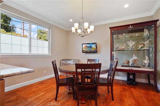 dining space featuring a chandelier, wood finished floors, baseboards, healthy amount of natural light, and ornamental molding